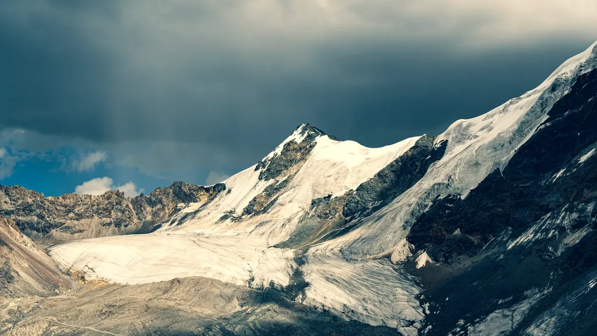 Snow-covered mountains under dramatic skies, showcasing natural beauty.