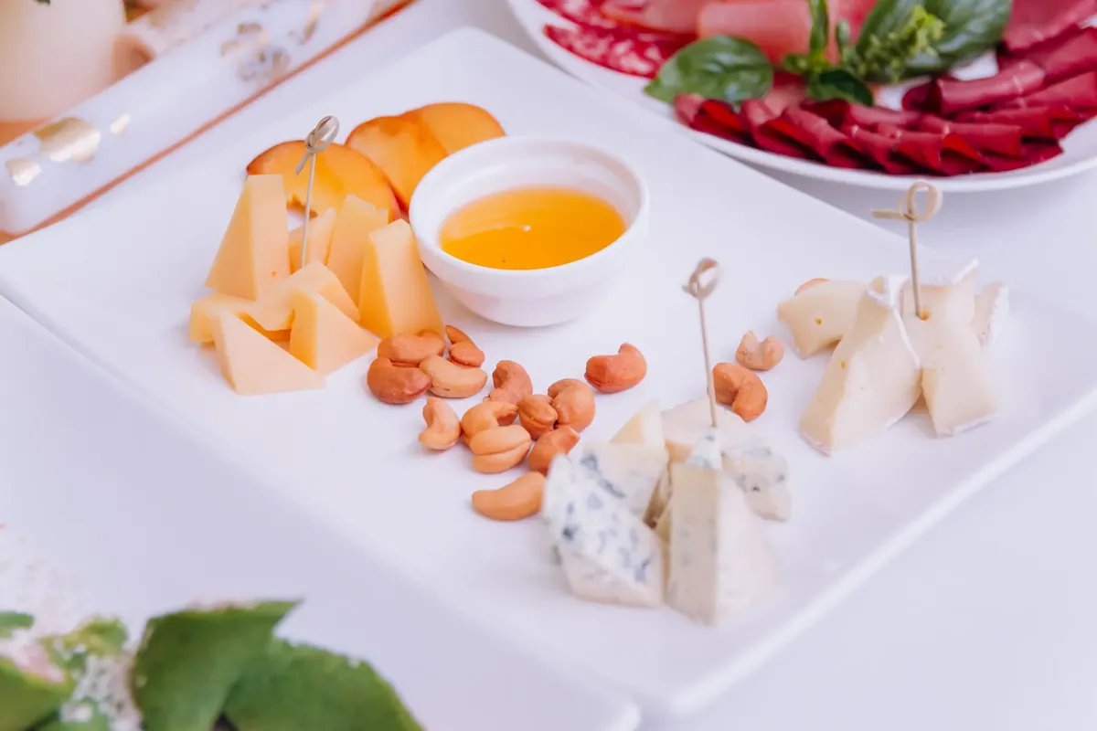 Assorted cheese platter with fresh fruits and nuts, perfect for a celebration.